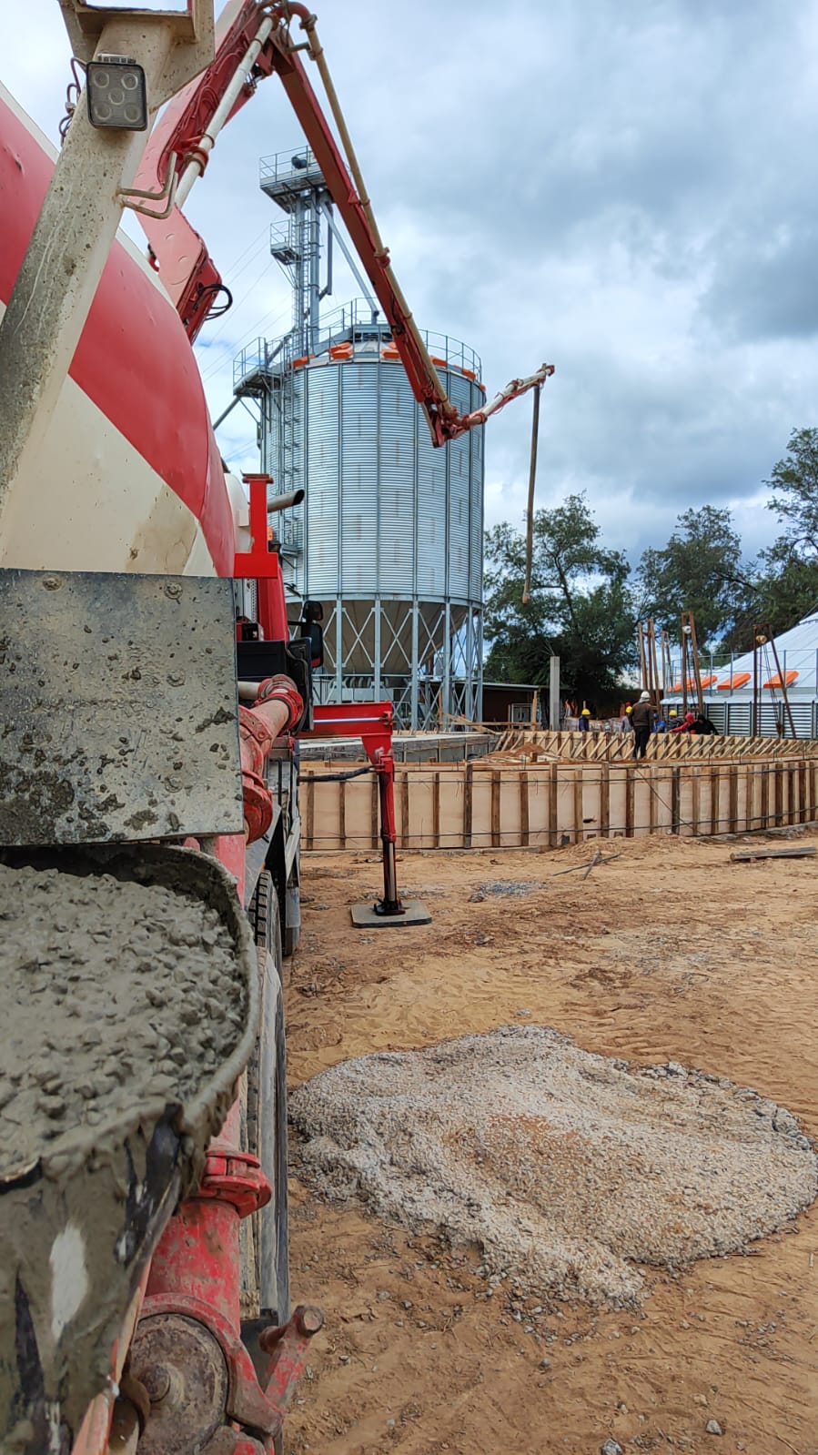 Brazo de bomba y mixer de HEC junto a silo en obra