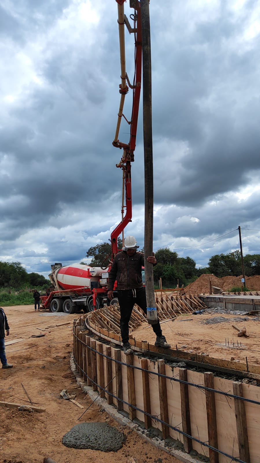 Obra con bomba de hormigon y silos al fondo